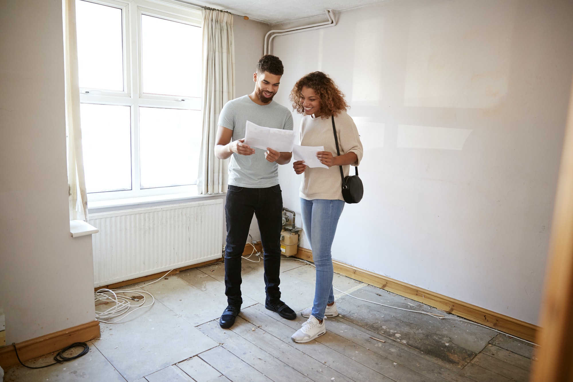 couple-buying-house-for-first-time-looking-at-house-survey-in-room-to-be-renovated-1.jpg